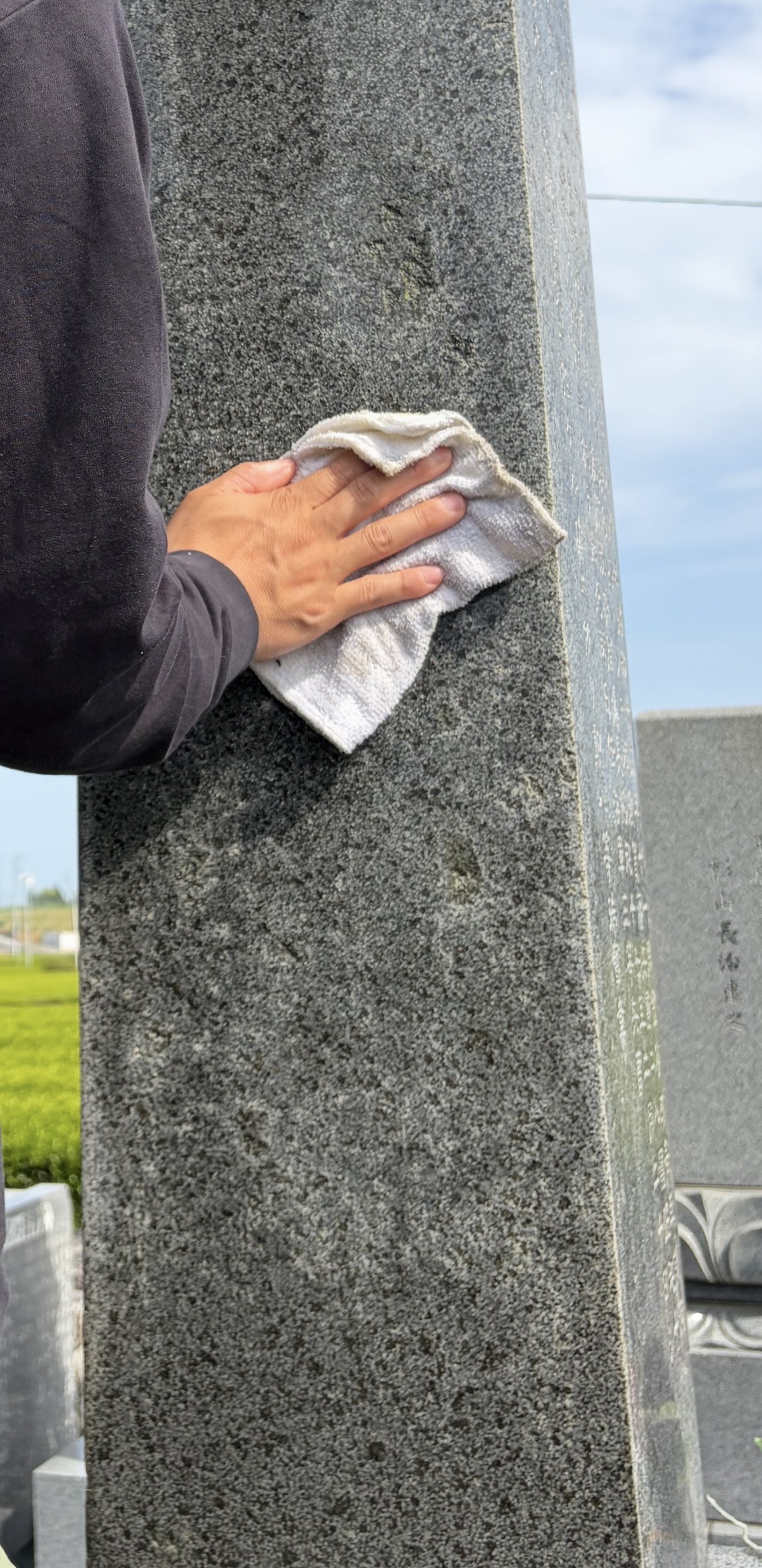 布で墓石を丁寧に水拭きする様子